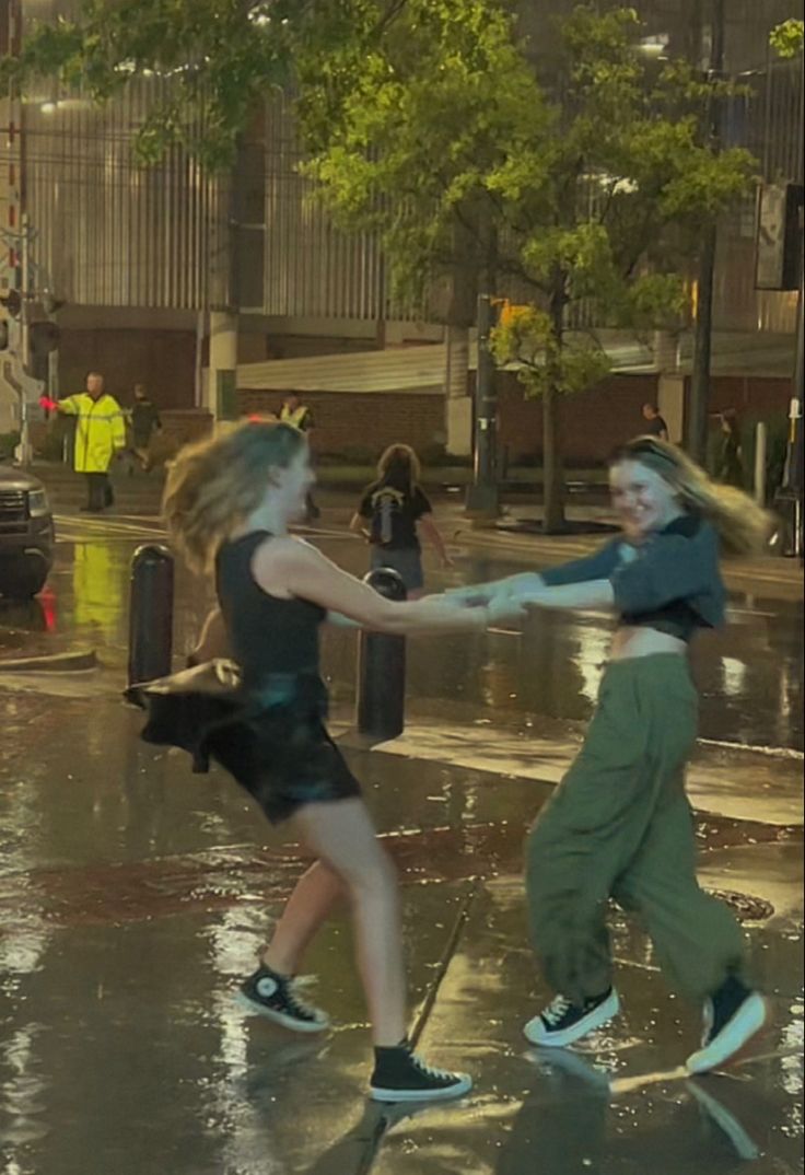 two young women are playing in the rain