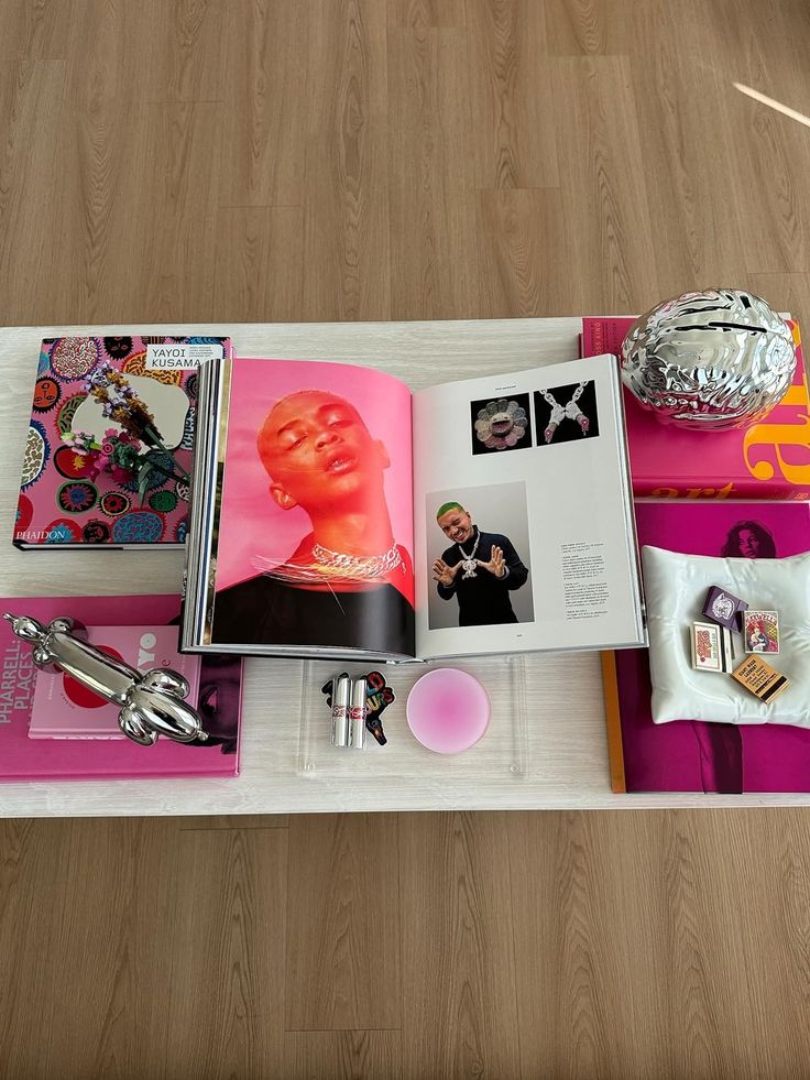 an open book on top of a table with various items around it and a silver vase