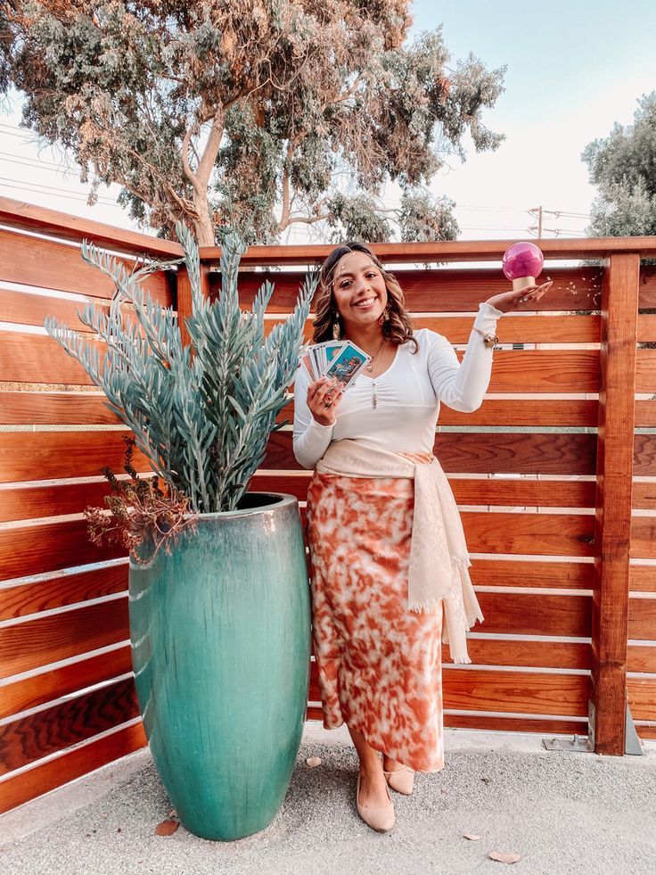 a woman standing next to a large potted plant