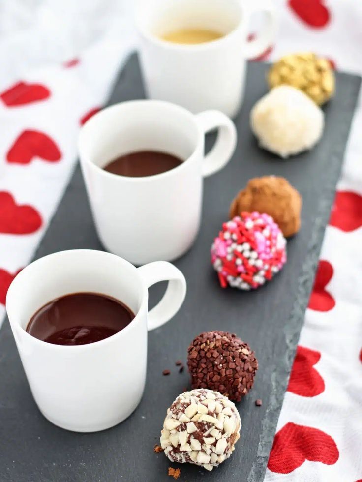 four different types of donuts and two cups of coffee on a tray with hearts