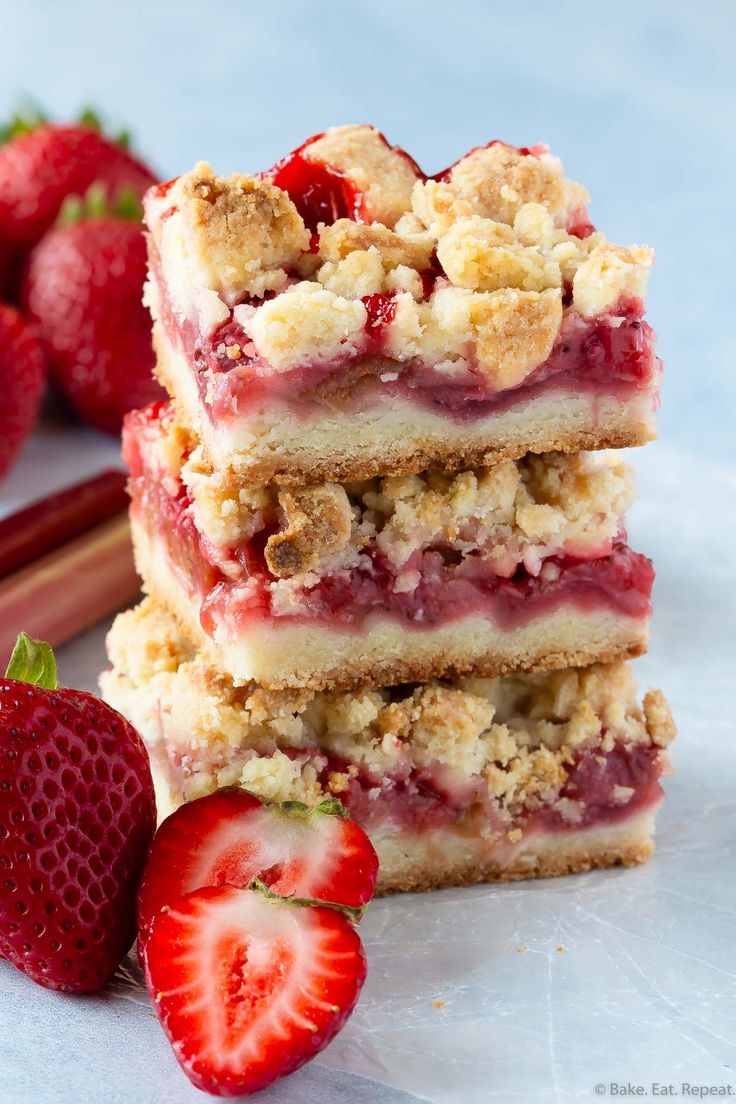 strawberry crumbler bars stacked on top of each other with strawberries next to them