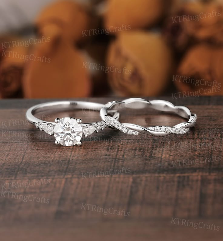 two wedding rings sitting on top of a wooden table with oranges in the background