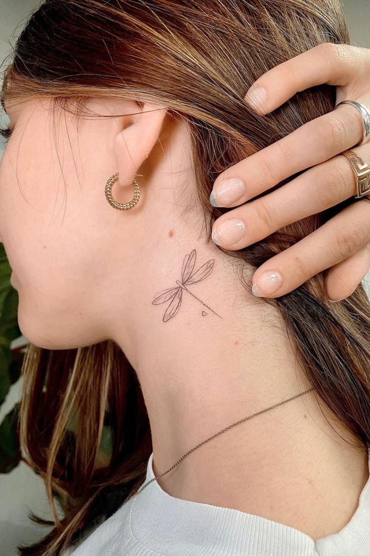 a woman with a small dragonfly tattoo on her left side behind her ear,