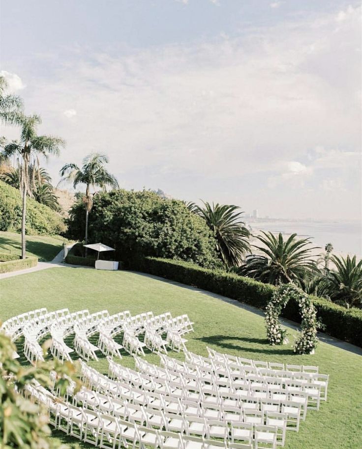 an outdoor ceremony set up with white chairs