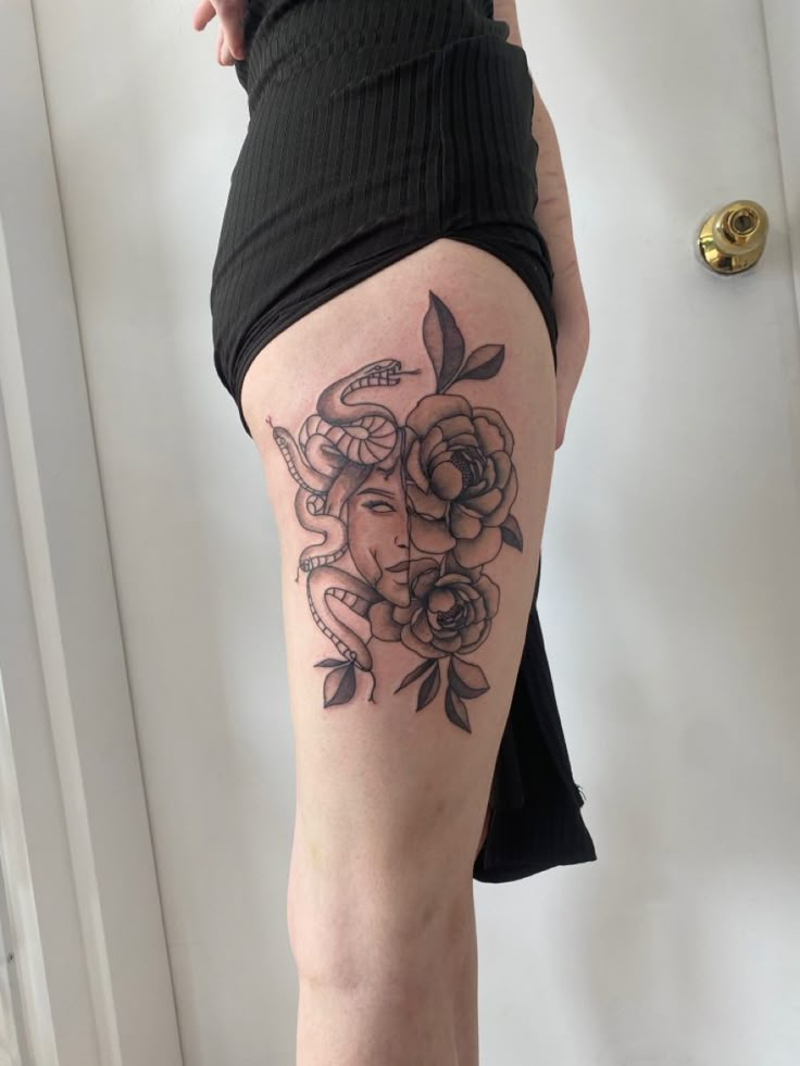 a woman's thigh with flowers and leaves on her leg, showing the tattoo design