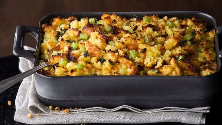 a casserole dish with stuffing in it on a cloth next to a spoon