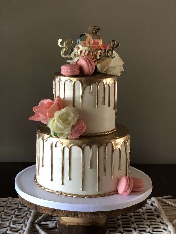 a three tiered cake with frosting and flowers on the top is sitting on a table