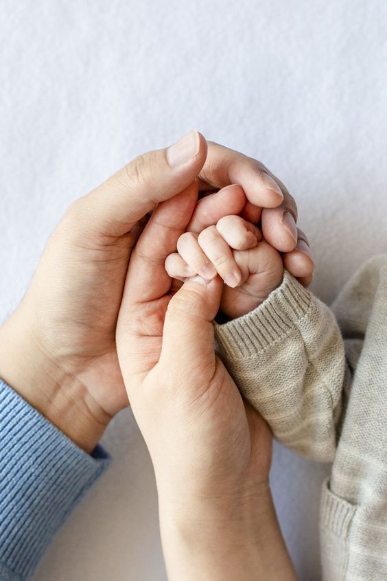 two hands holding each other on top of a white surface