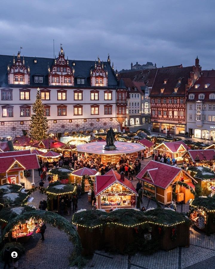 an outdoor christmas market with lots of lights and decorations on display in front of buildings