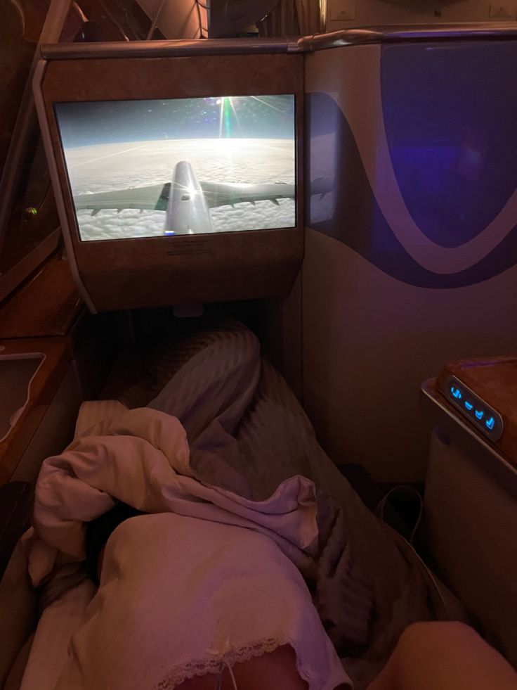 a person laying in bed watching television on an airplane with the tv screen turned off