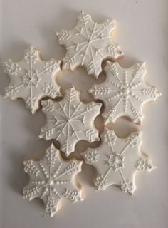 some cookies are decorated like snowflakes on a white tablecloth and placed in the shape of an ornament