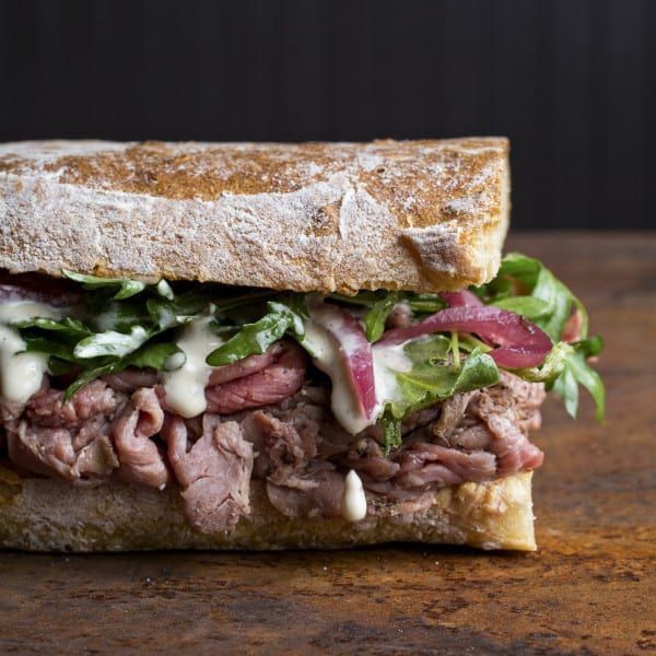 a sandwich with meat, lettuce and sauce on it sitting on a table