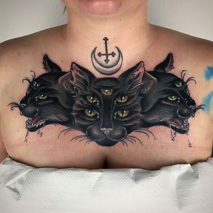 a woman's chest with three black cats and a crescent tattoo on her chest