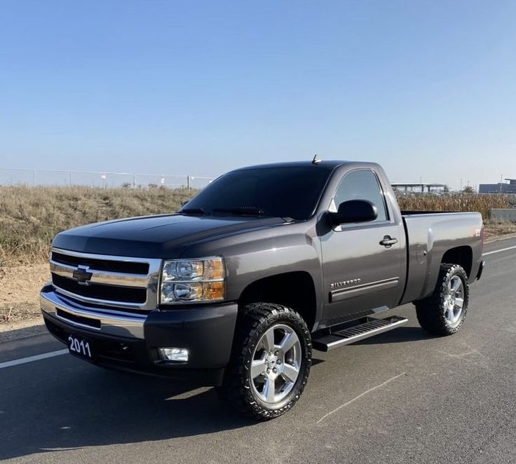 a silver truck is parked on the side of the road