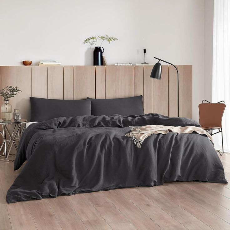 a bed with black sheets and pillows in a room