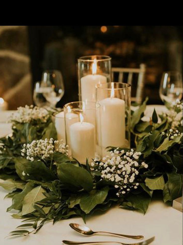 candles and greenery are arranged on the table for a formal dinner or wedding reception