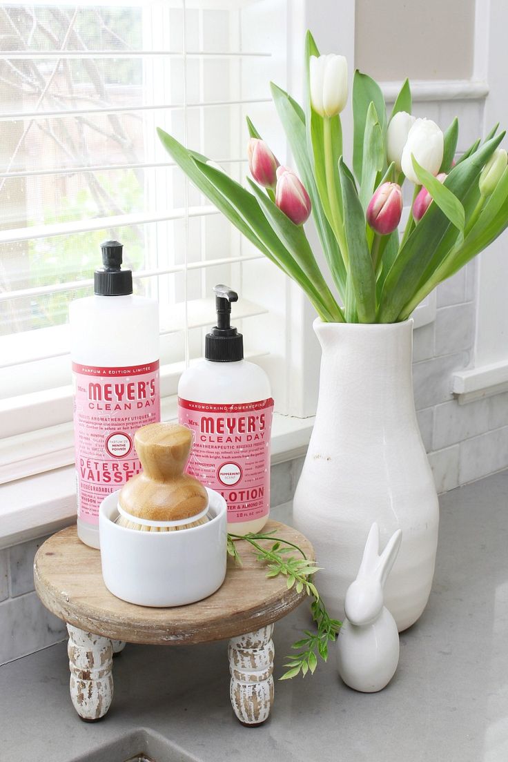 two bottles of soap sitting on top of a counter next to a vase with tulips