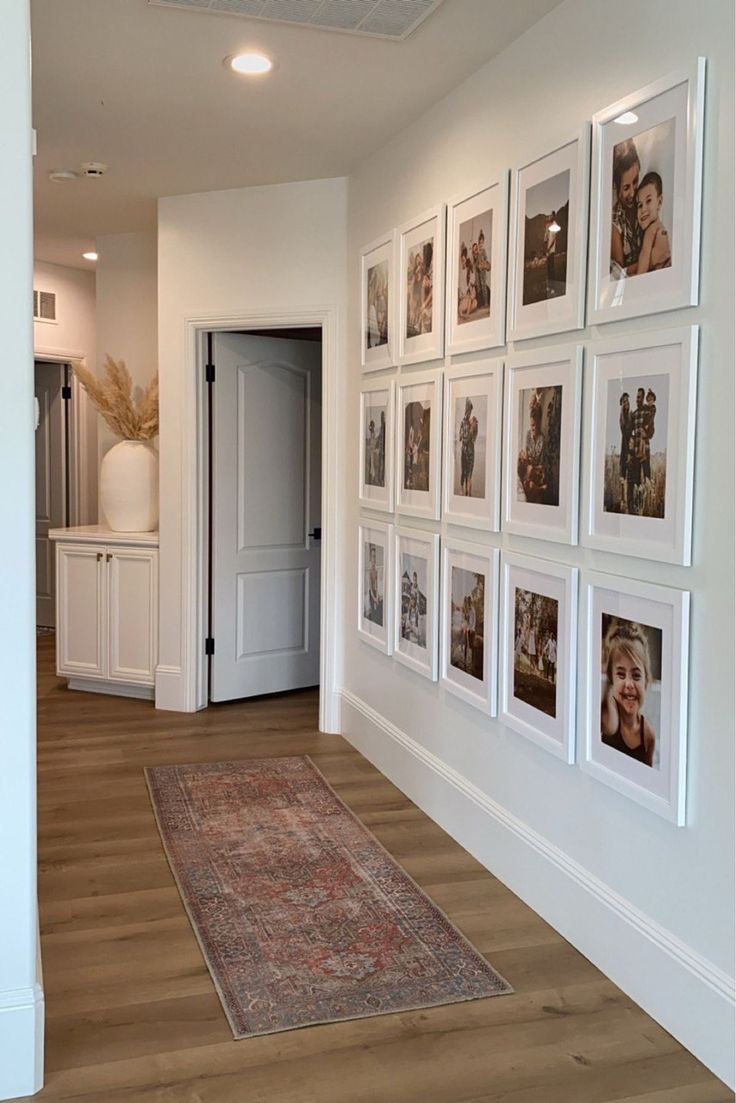 a hallway with pictures on the wall and a rug in front of an open door