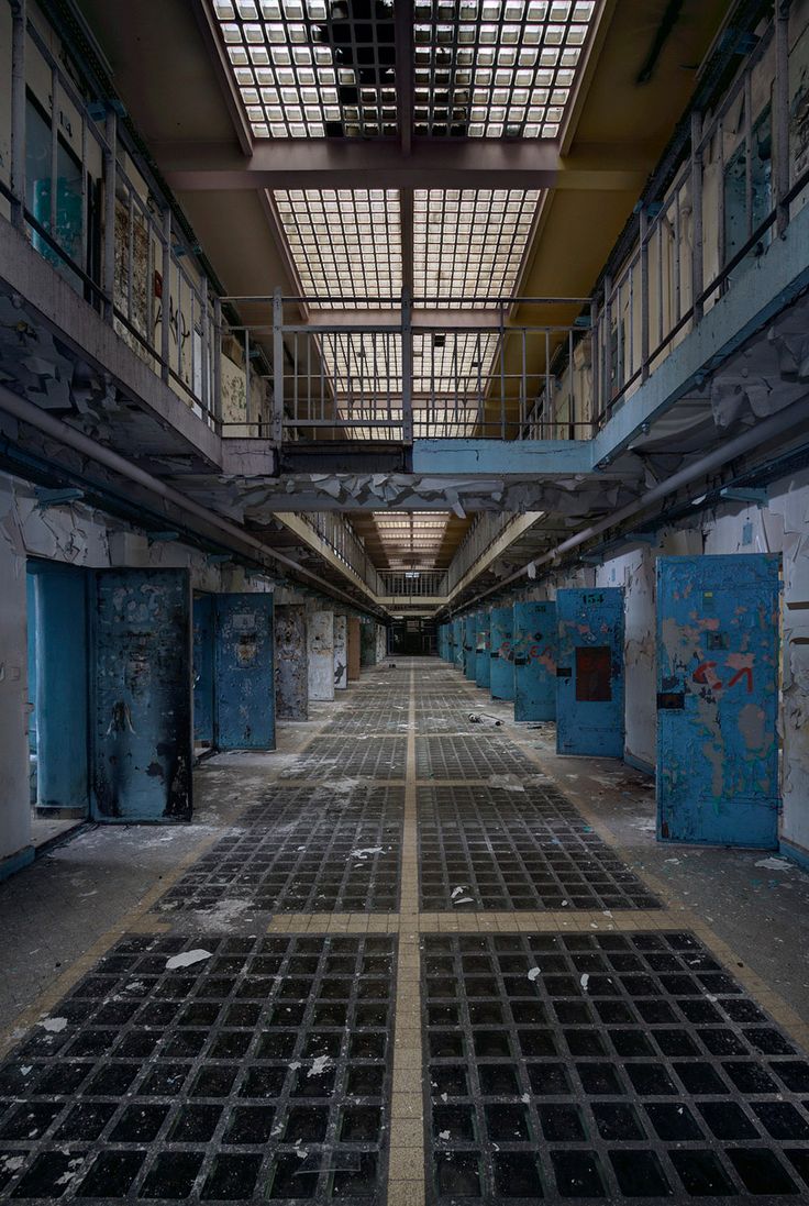 an empty building with lots of windows and metal grates on the floor in front of it