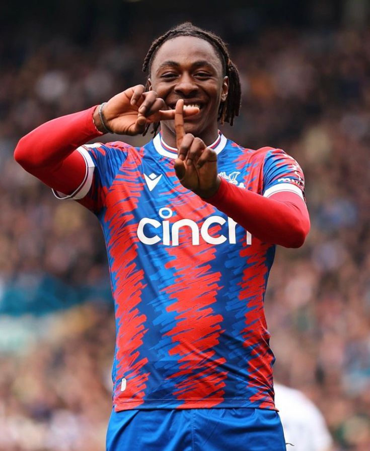 a man with dreadlocks points to the camera while standing in front of a crowd