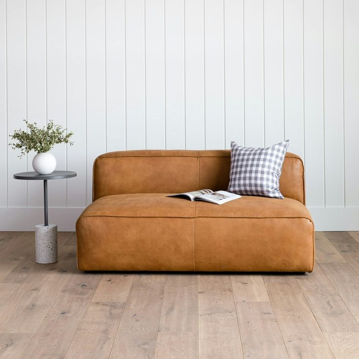 a brown leather couch sitting on top of a hard wood floor next to a table