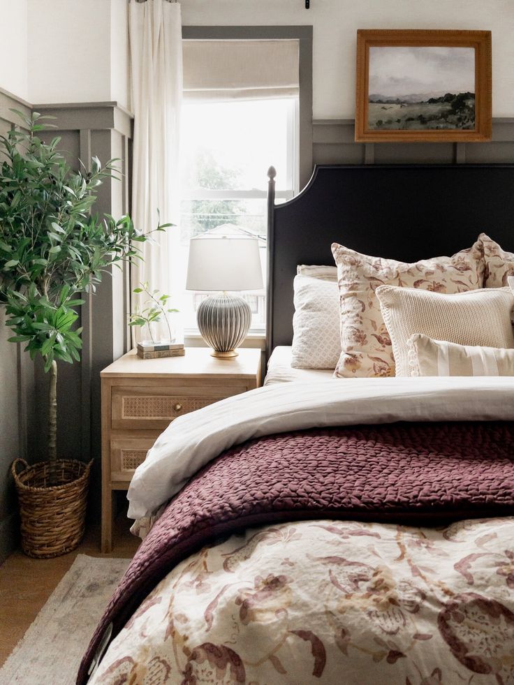 a bedroom with a bed, nightstand and potted plant on the side table in front of it