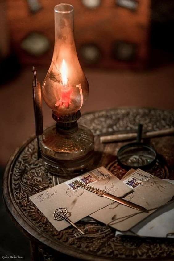 an old fashioned lamp sitting on top of a table next to envelopes and scissors