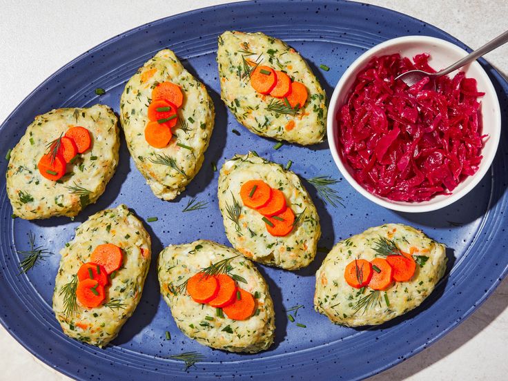 a blue plate topped with biscuits covered in veggies next to a bowl of red cabbage