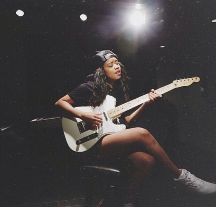 a woman sitting on top of a chair holding a guitar