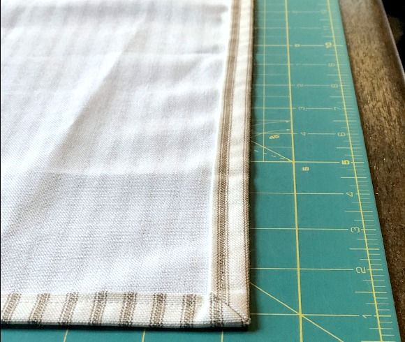 a piece of cloth sitting on top of a cutting board next to a knife and ruler