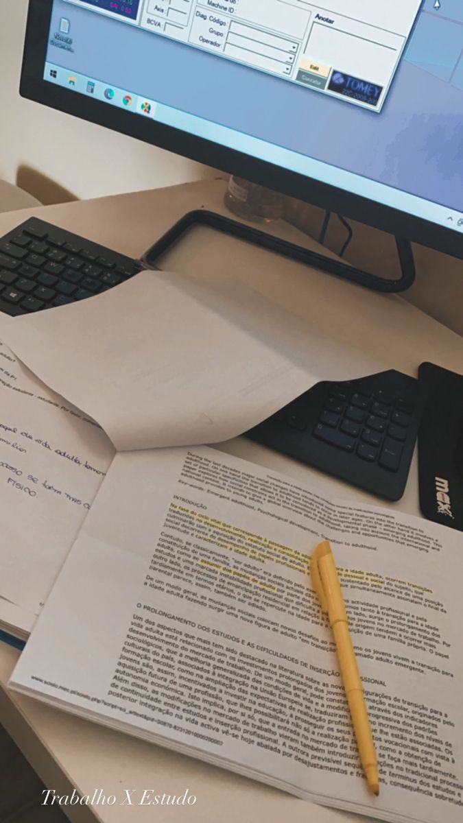 a computer monitor sitting on top of a desk next to a keyboard and paper with a pen