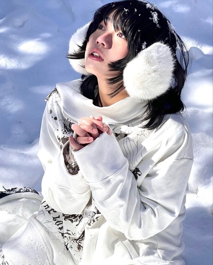 a woman sitting in the snow wearing a white outfit