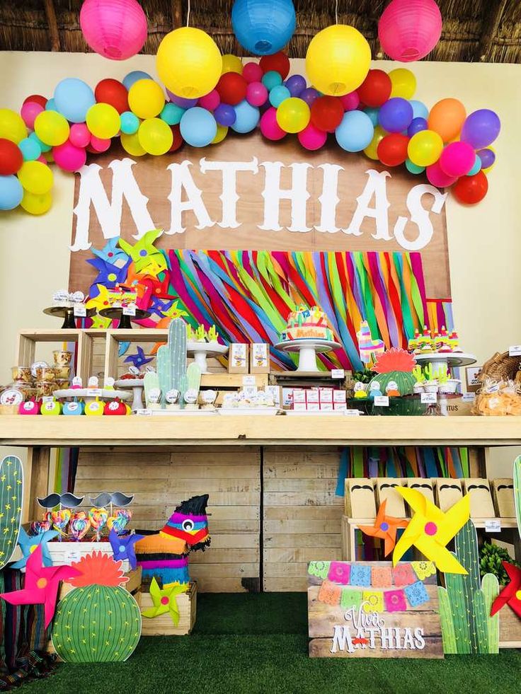 a table filled with lots of colorful items and balloons on top of it's head