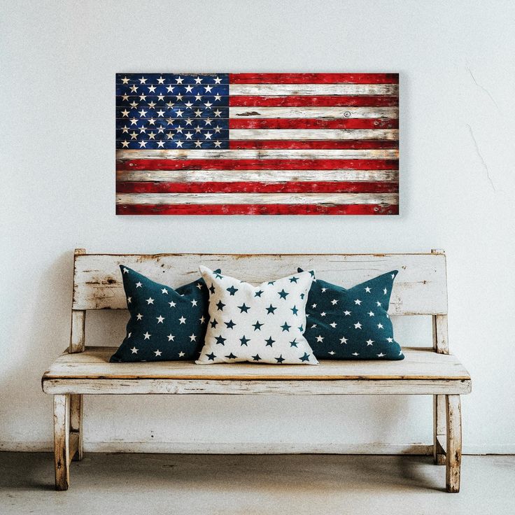 a wooden bench with two pillows on it in front of an american flag wall hanging