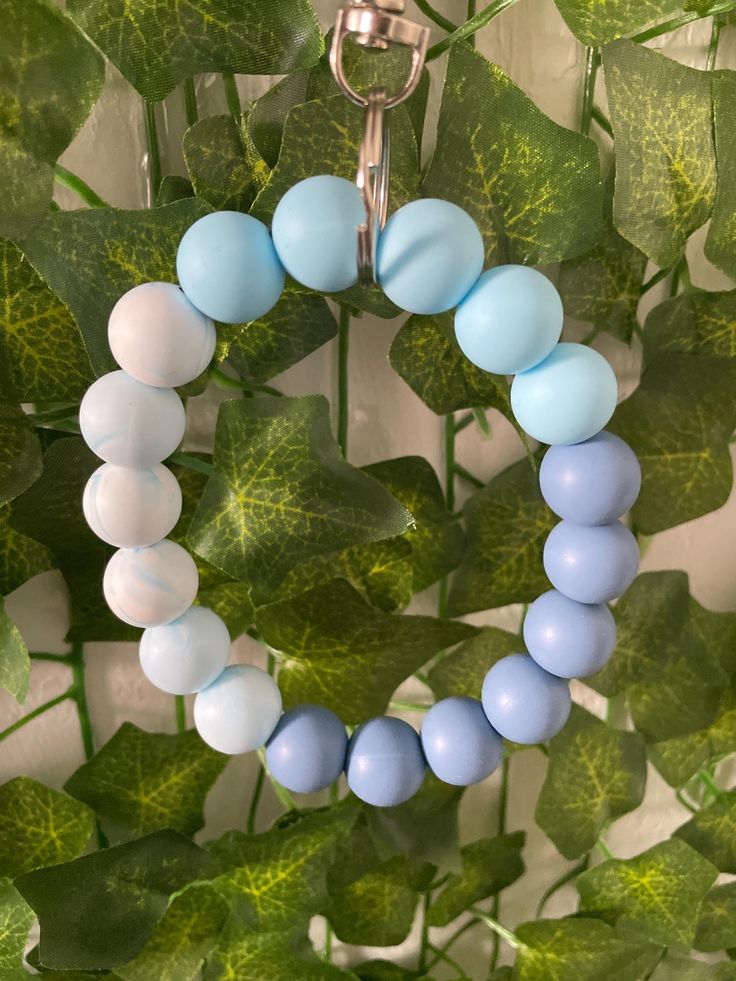 a blue and white beaded necklace hanging from a green plant