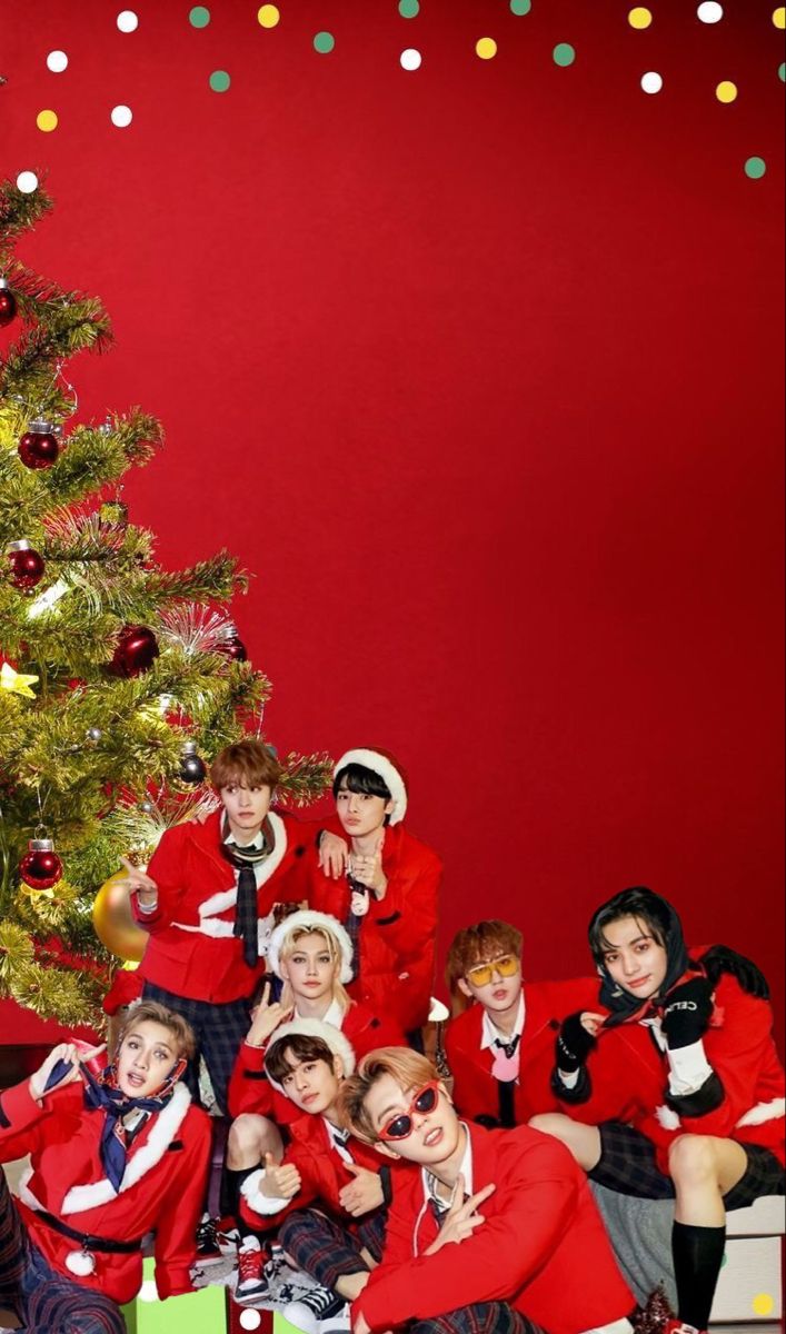 a group of young people posing in front of a christmas tree