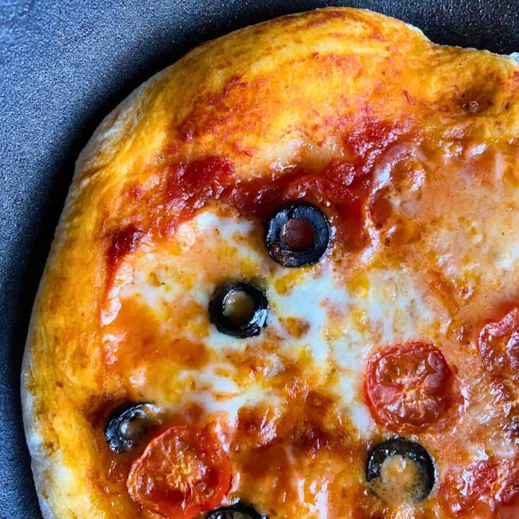 a pizza with olives and pepperoni on it is sitting on a blue surface