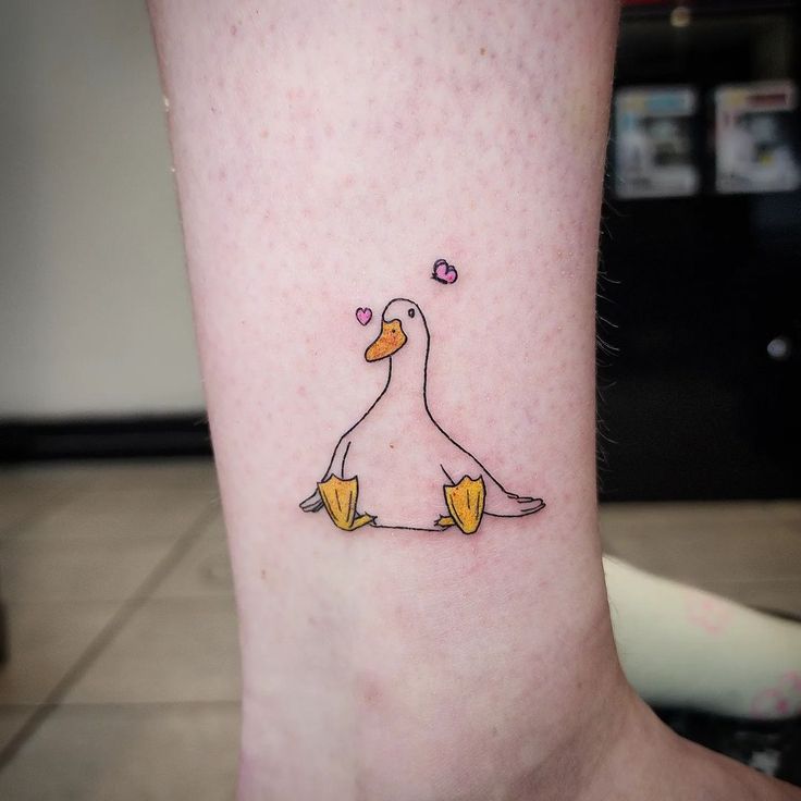 a small tattoo on the ankle of a woman's leg with two ducks sitting next to each other