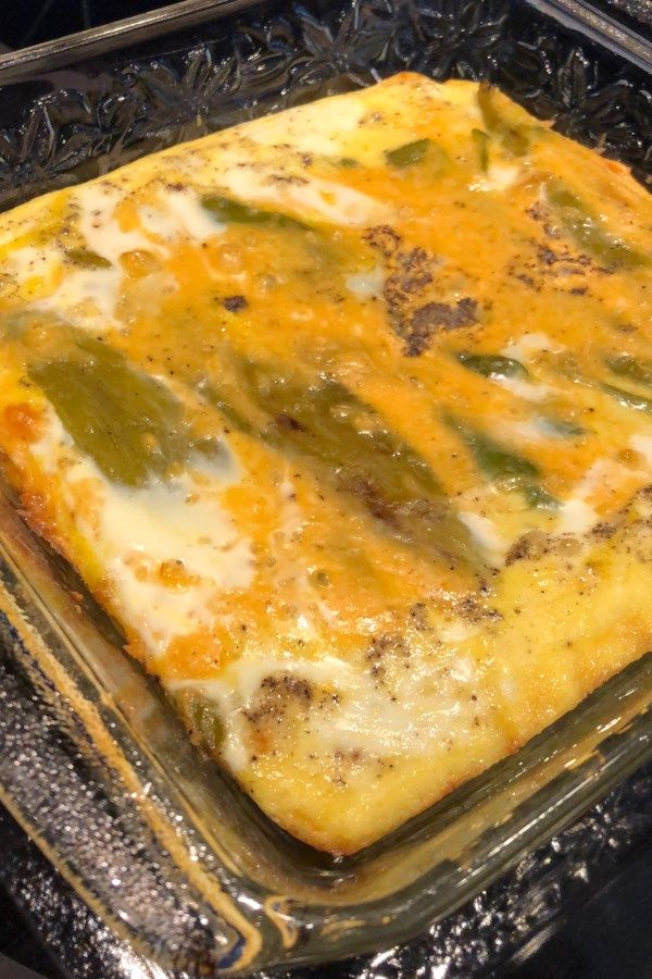 a square casserole with cheese and green peppers in it on a baking tray