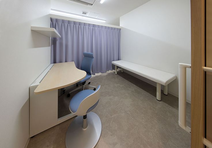 an empty room with a desk, chair and shelf next to a curtained window