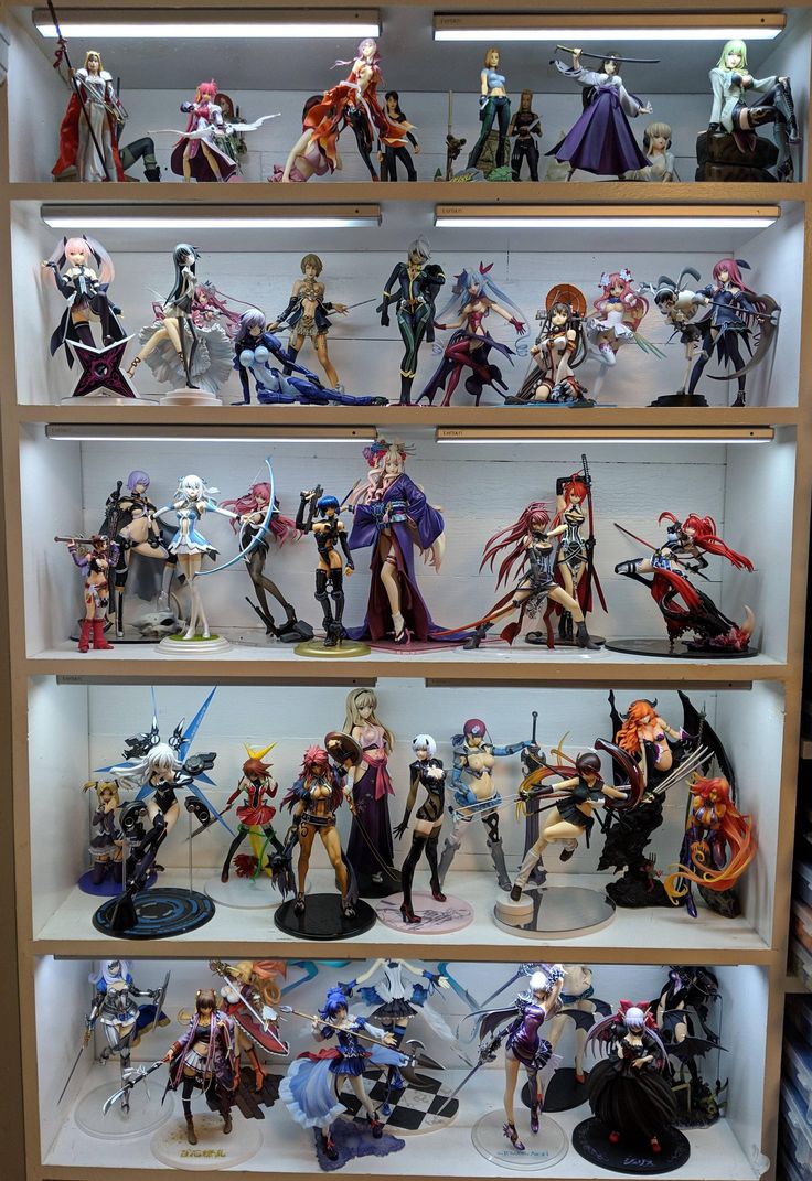 a display case filled with lots of action figures on top of wooden shelves in front of a white wall