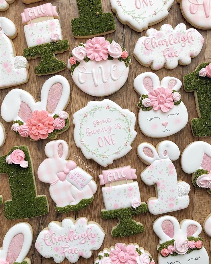 some decorated cookies on top of a wooden table with pink and white frosted decorations