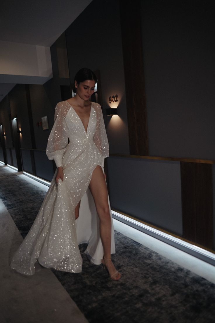 a woman in a white dress is walking down the hallway with her leg on the floor