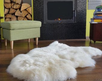 a white sheepskin rug on the floor in front of a fire place and chair