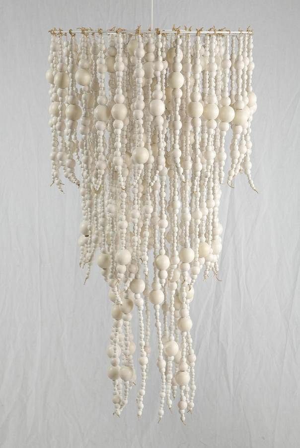 a white chandelier with beads hanging from it's side on a wall