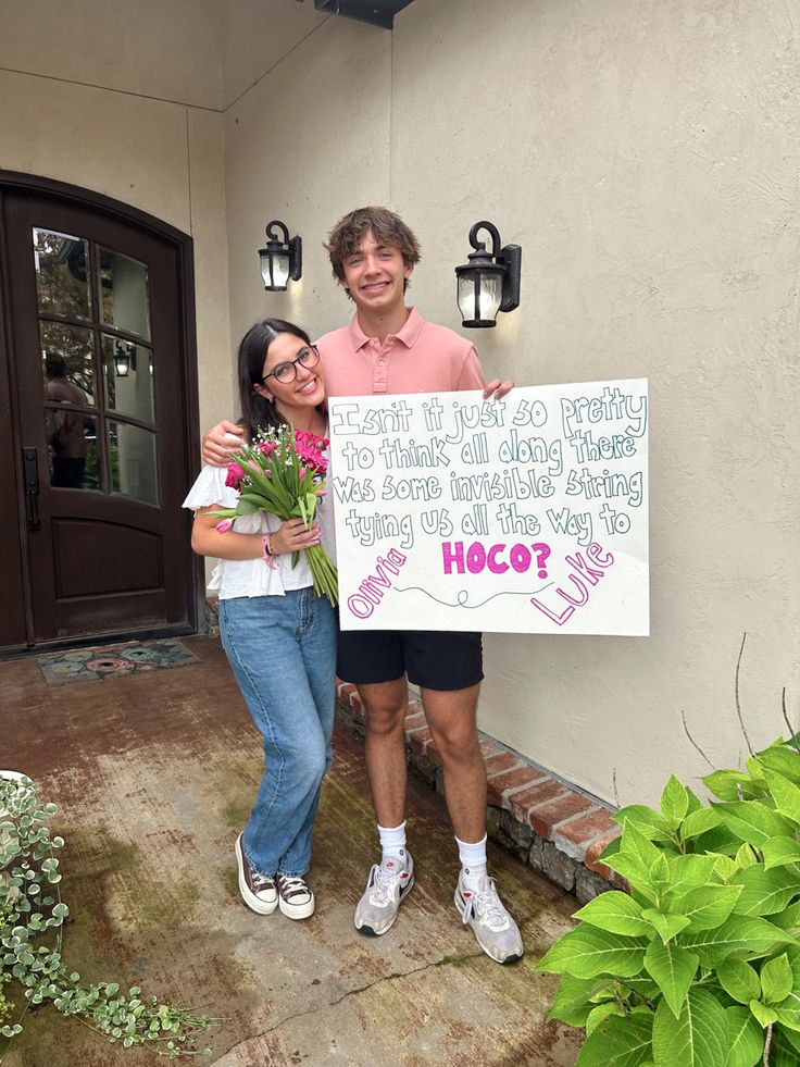 two people standing next to each other holding a sign