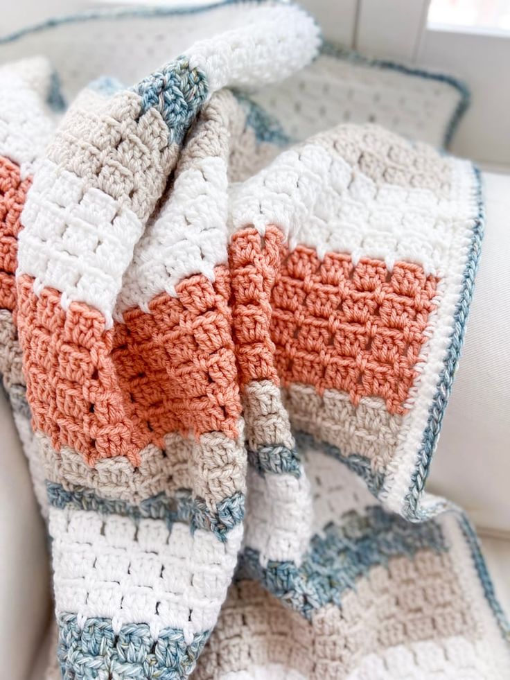 a crocheted blanket sitting on top of a couch