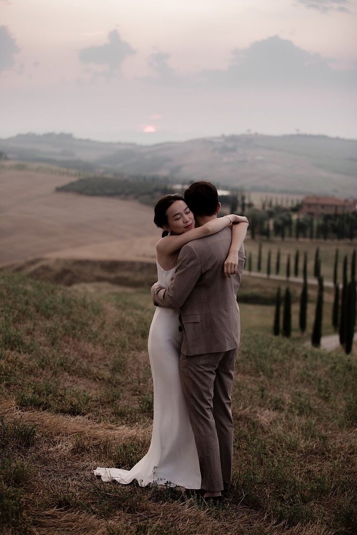 a bride and groom embracing in the countryside