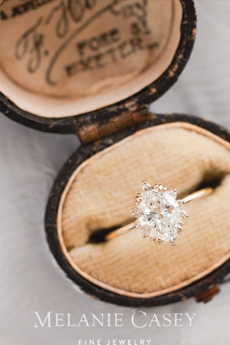 an old diamond ring in a wooden box with writing on the side and inside it