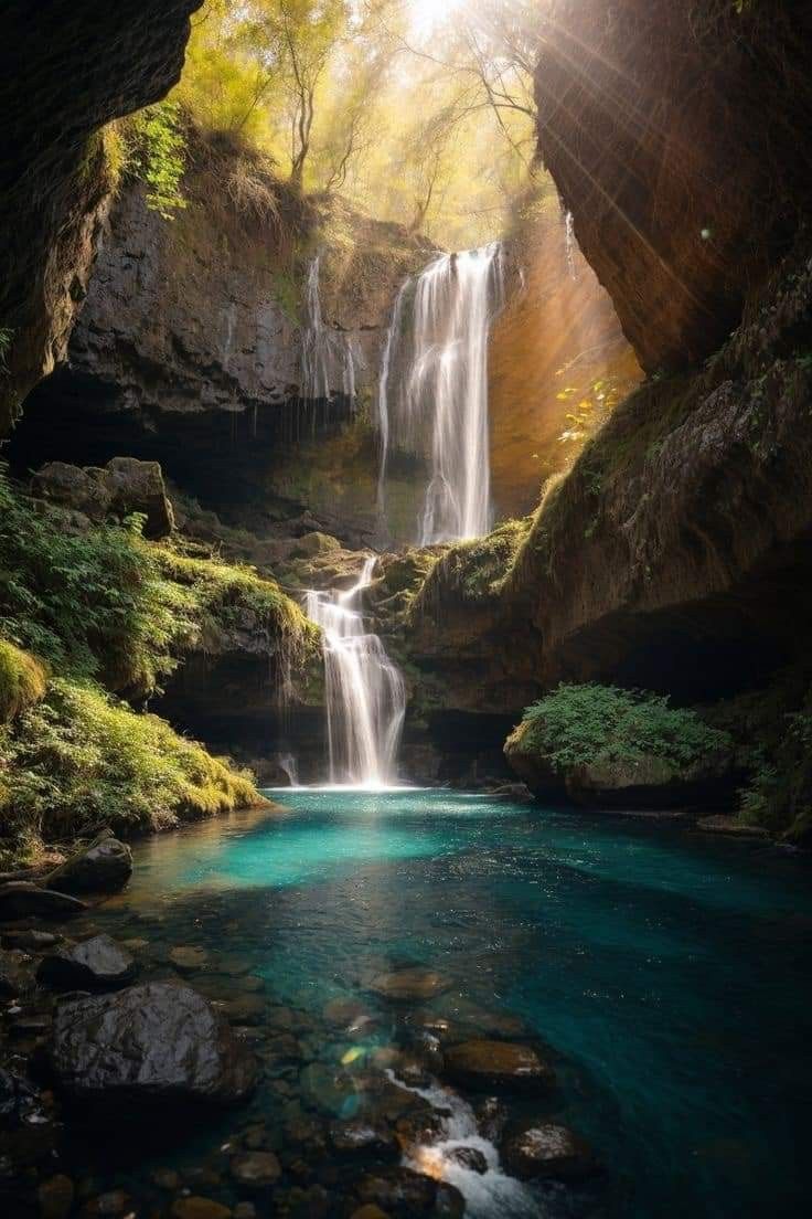 there is a small waterfall in the middle of this river and it's blue water